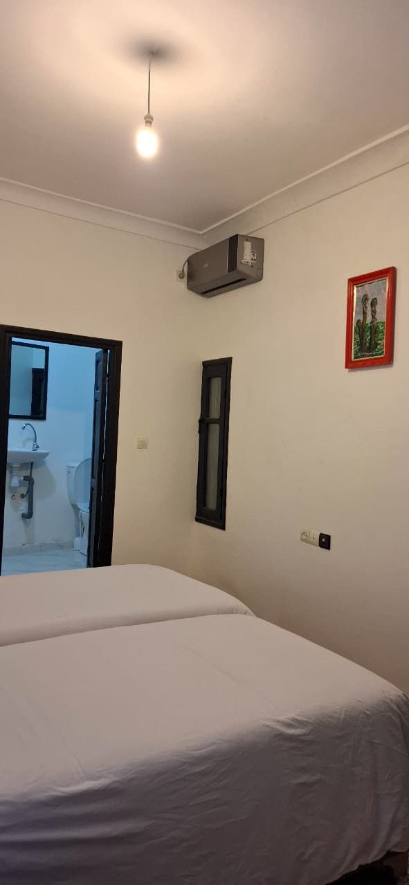 A bedroom with a bed, a door leading to a bathroom, and a ceiling light.