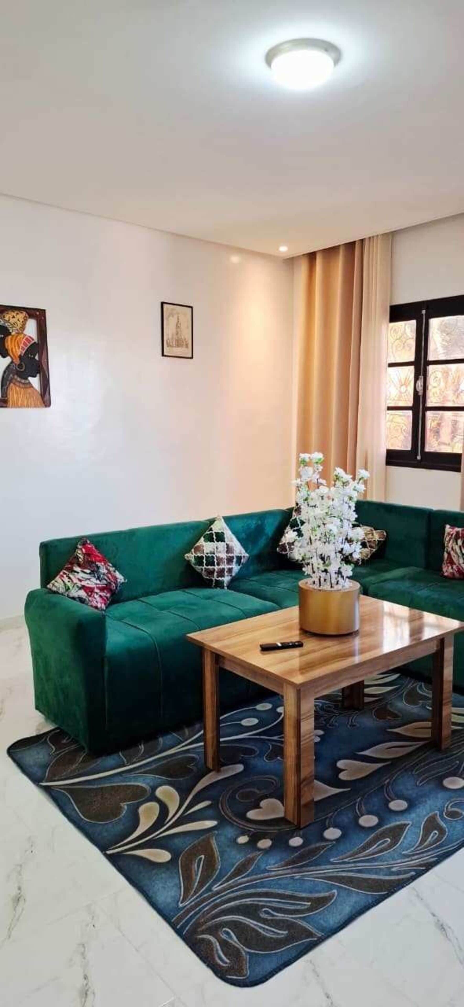 A living room with a green sofa, a wooden coffee table, and a patterned rug.