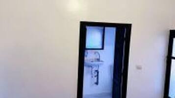 Une pièce comprenant un lit, une fenêtre et une porte donnant sur une salle de bain.