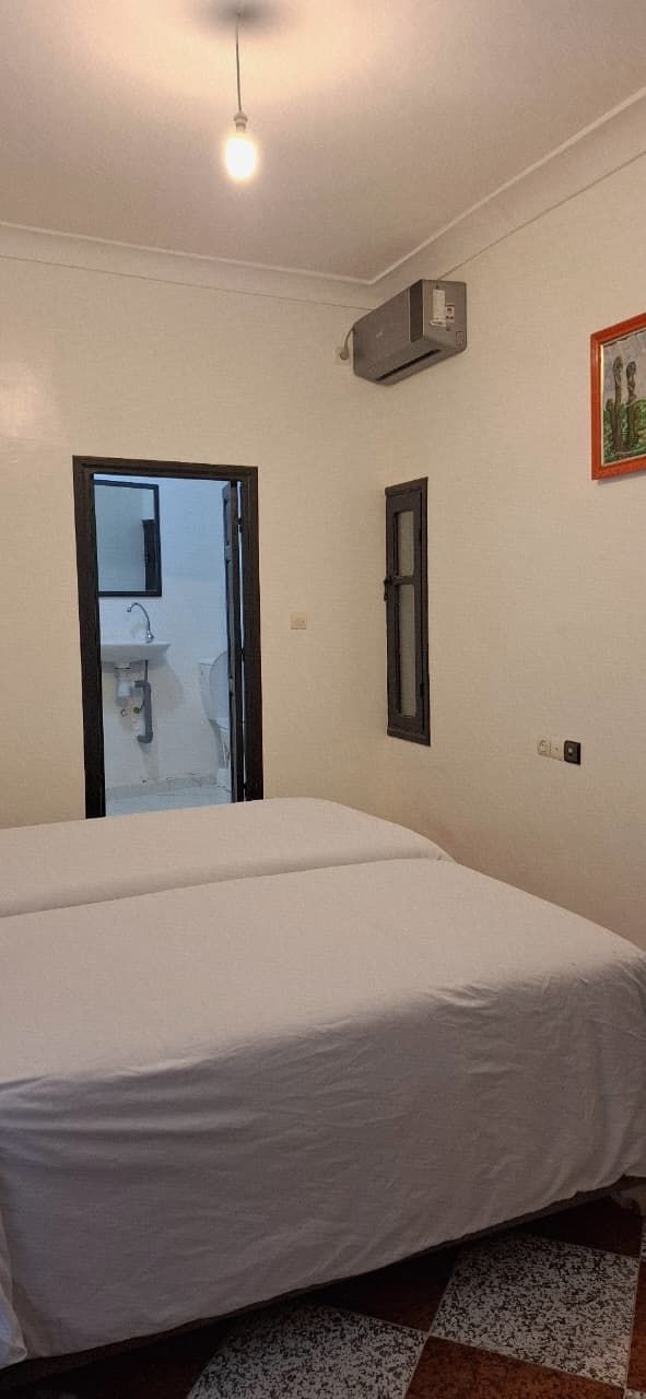 Een slaapkamer met een bed, een deur naar een badkamer en een airconditioning op de muur.