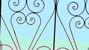 Une grille en métal décorative, ornée de motifs complexes, qui fait probablement partie de l’entrée d’un bâtiment ou d’un balcon.