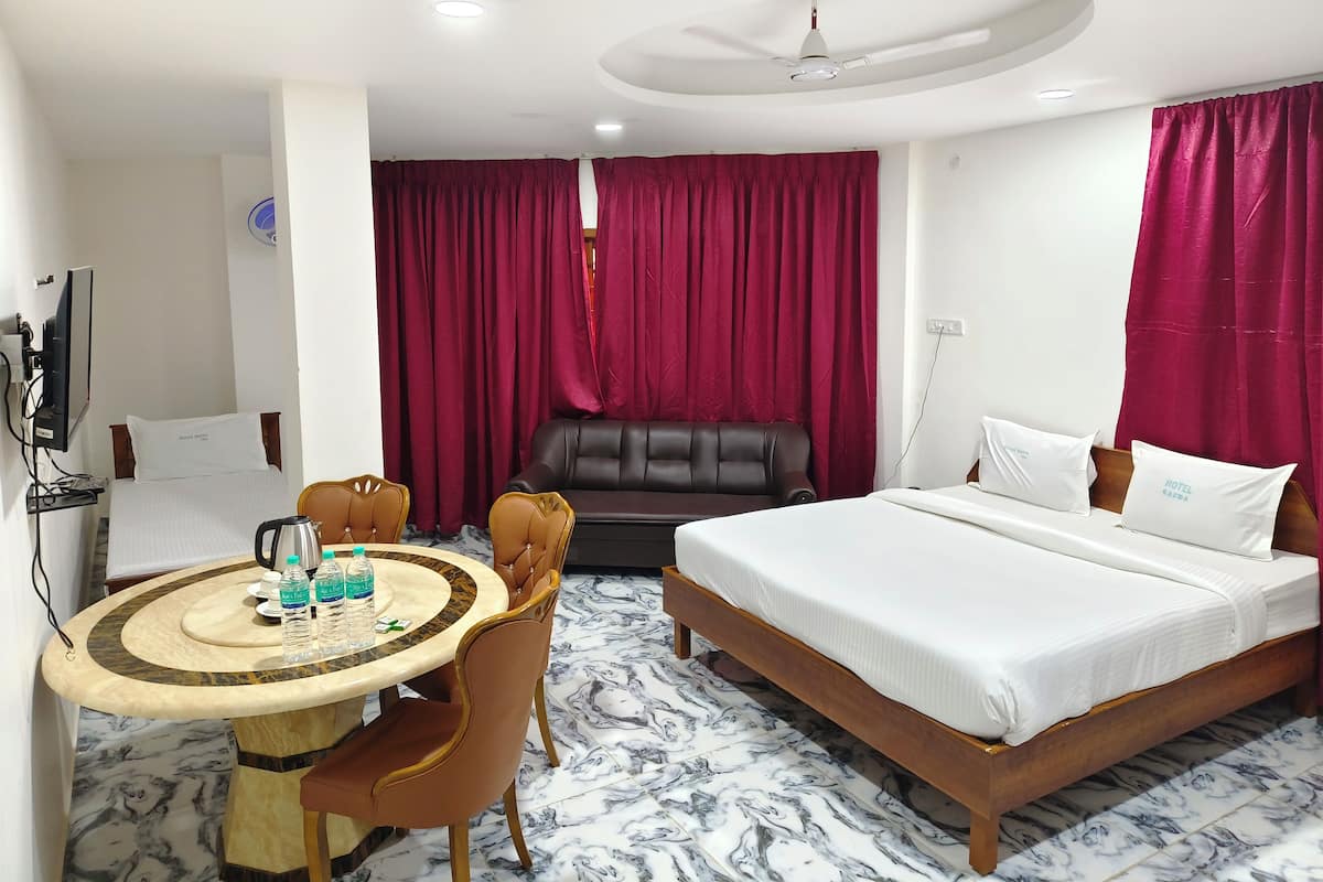 A hotel room with a bed, a desk with a chair, a sofa, and a TV.