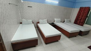 A hotel room with three single beds, a small table, and a telephone. - hotel safra (Chennai)