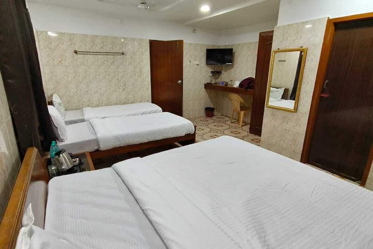 A hotel room with two beds, a desk, a chair, a television, and a mirror.