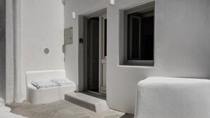 Una habitación con paredes blancas, un pequeño banco y un ventanal.