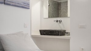 Un baño con un lavamanos blanco, un espejo y una ducha.