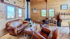 A wooden cabin interior with a leather sofa, a coffee table, and a fireplace.