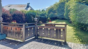 A wooden deck with a railing, a birdhouse, and a potted plant.
