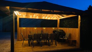 An outdoor wooden deck with a covered seating area, string lights, and a grill. - Berry cottage: covered terrace, ping-pong, near Beauval Zoo and Valençay Castle (Vicq-sur-Nahon)
