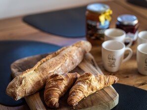 Una tabla de madera con dos cruasanes y una baguette.