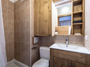 A bathroom with a white sink, wooden cabinets, and a shower area. - Duplex 7 pers. 2 balconies, station center, WIFI (La Plagne Montalbert)