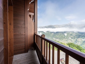 Un balcón de madera con vistas a un paisaje montañoso y nubes.