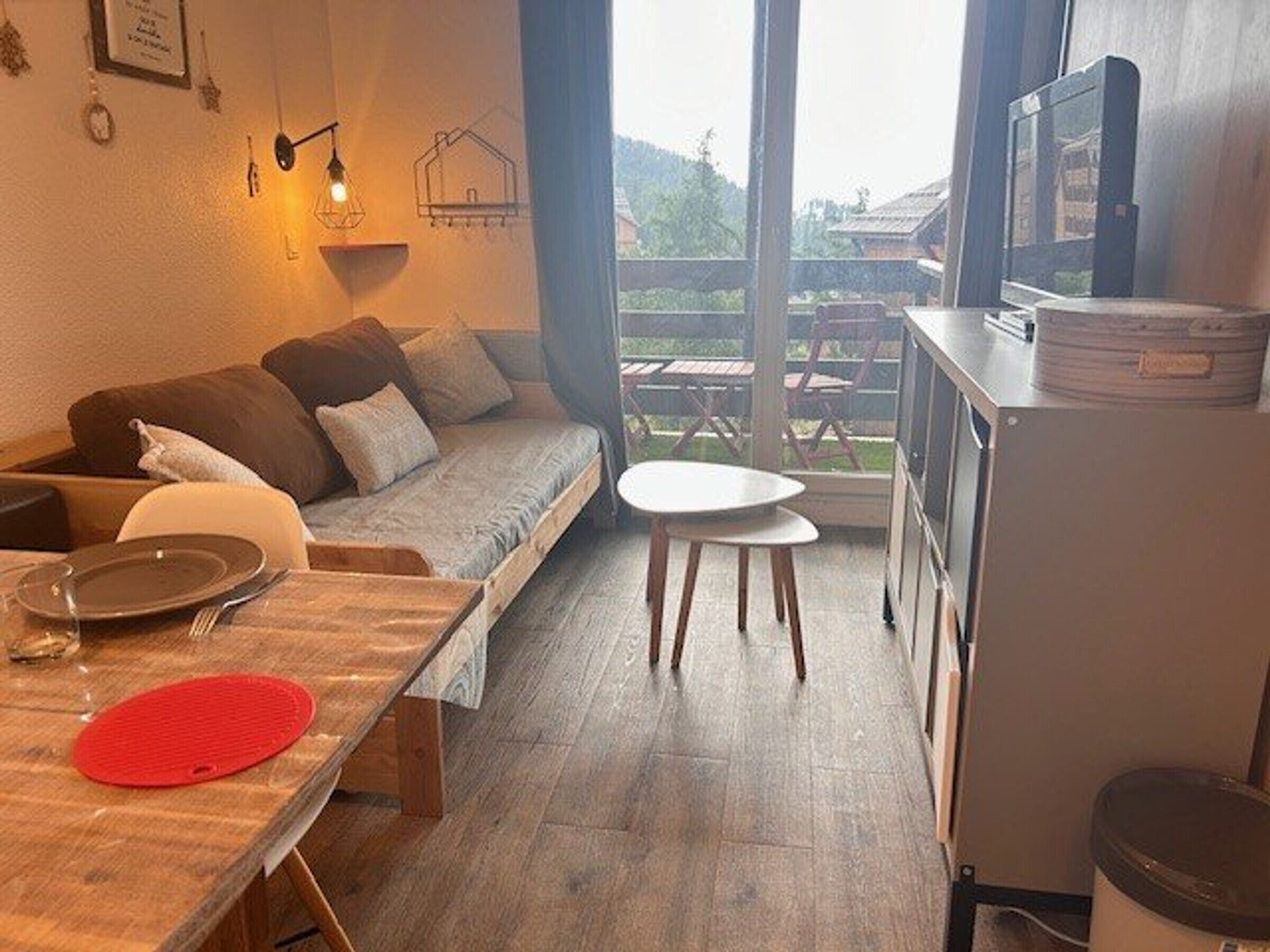 Een ruimtelijk ingerichte leefruimte met een bank, een eettafel, een kitchenette en uitzicht door een glazen deur.