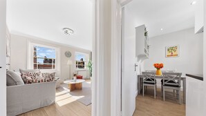 A modern living room with a grey sofa, a coffee table, and a dining area with a table and chairs. - Stunning 2B Flat in South Kensington Near Station (London)