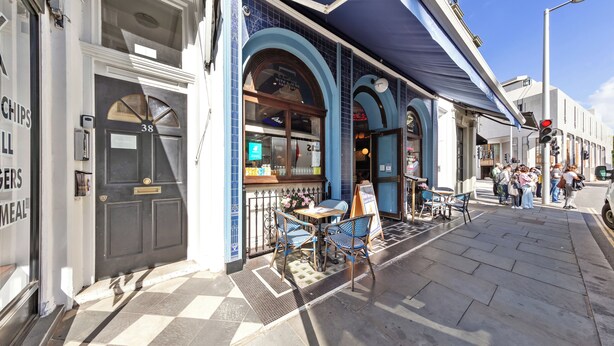 A cafe with outdoor seating, a black door with the number 38, and a blue awning. - Stunning 2B Flat in South Kensington Near Station (London)
