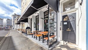 A restaurant with outdoor seating and a sign advertising fish & chips, grill burgers, and kids' meals. - Stunning 2B Flat in South Kensington Near Station (London)