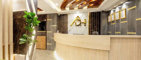 A modern reception area with a curved reception desk, marble flooring, and a wooden ceiling with recessed lighting.