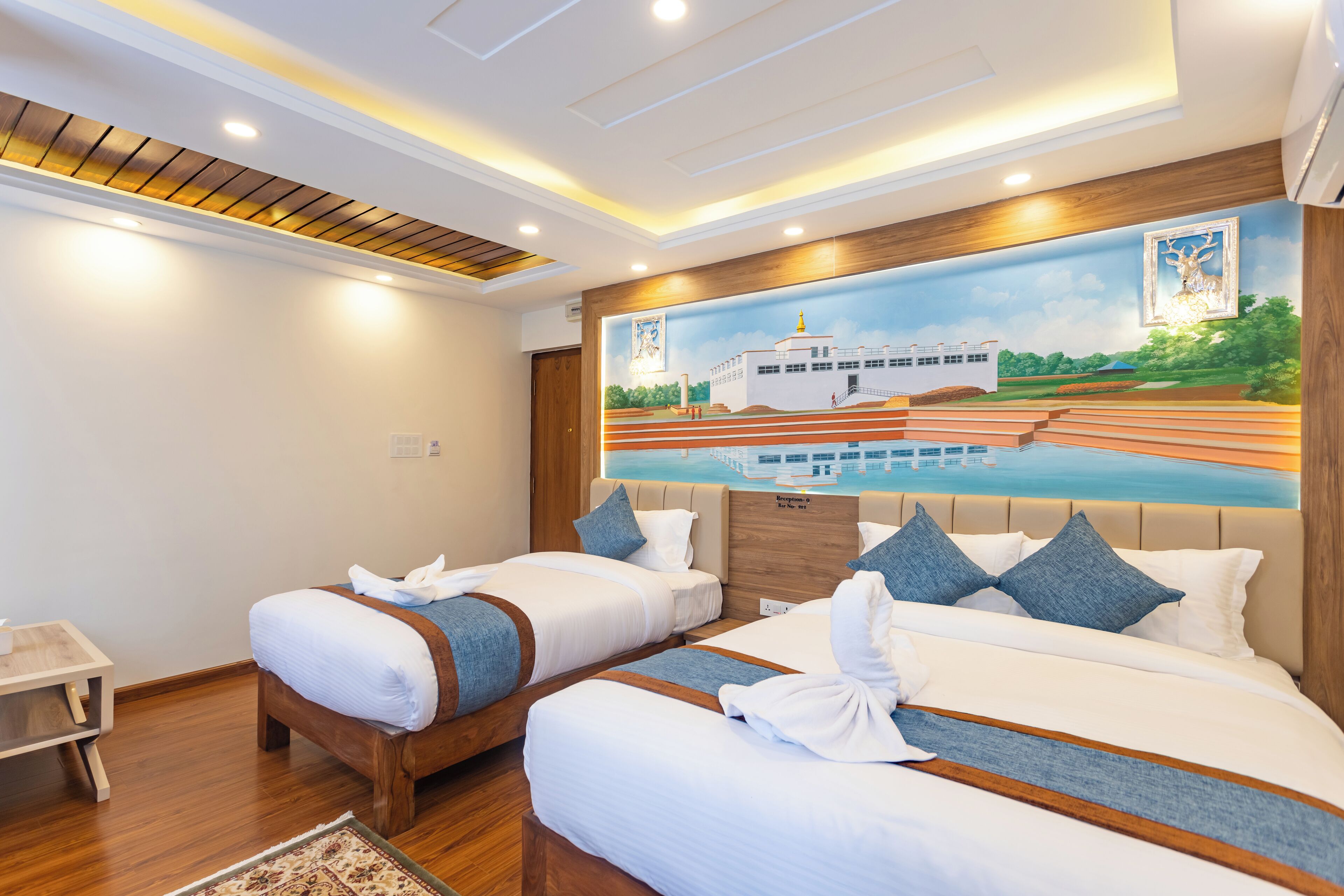 A hotel room with two beds, a wooden headboard, a mural of a boat on water, and a small side table.