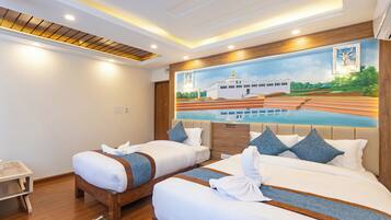A hotel room with two beds, a wooden headboard, a mural of a boat on water, and a small side table.