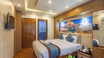 A hotel room with a large bed, wooden paneling, a mural, a television, and a small table with amenities.