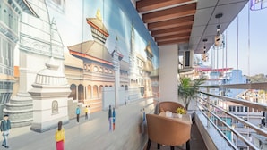 Un interior moderno con un mural de arquitectura tradicional, un balcón con vistas y una zona de estar.