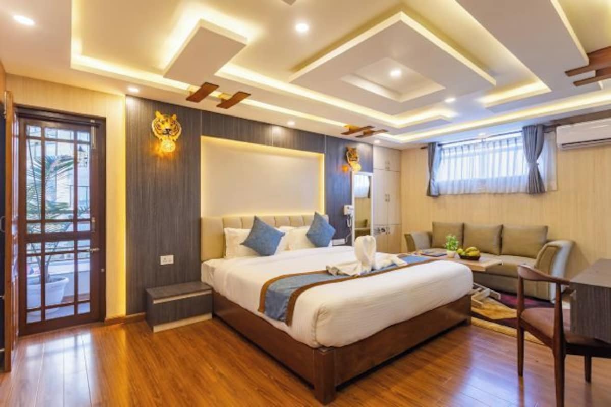 A modern hotel room with a large bed, a desk, and a sofa.