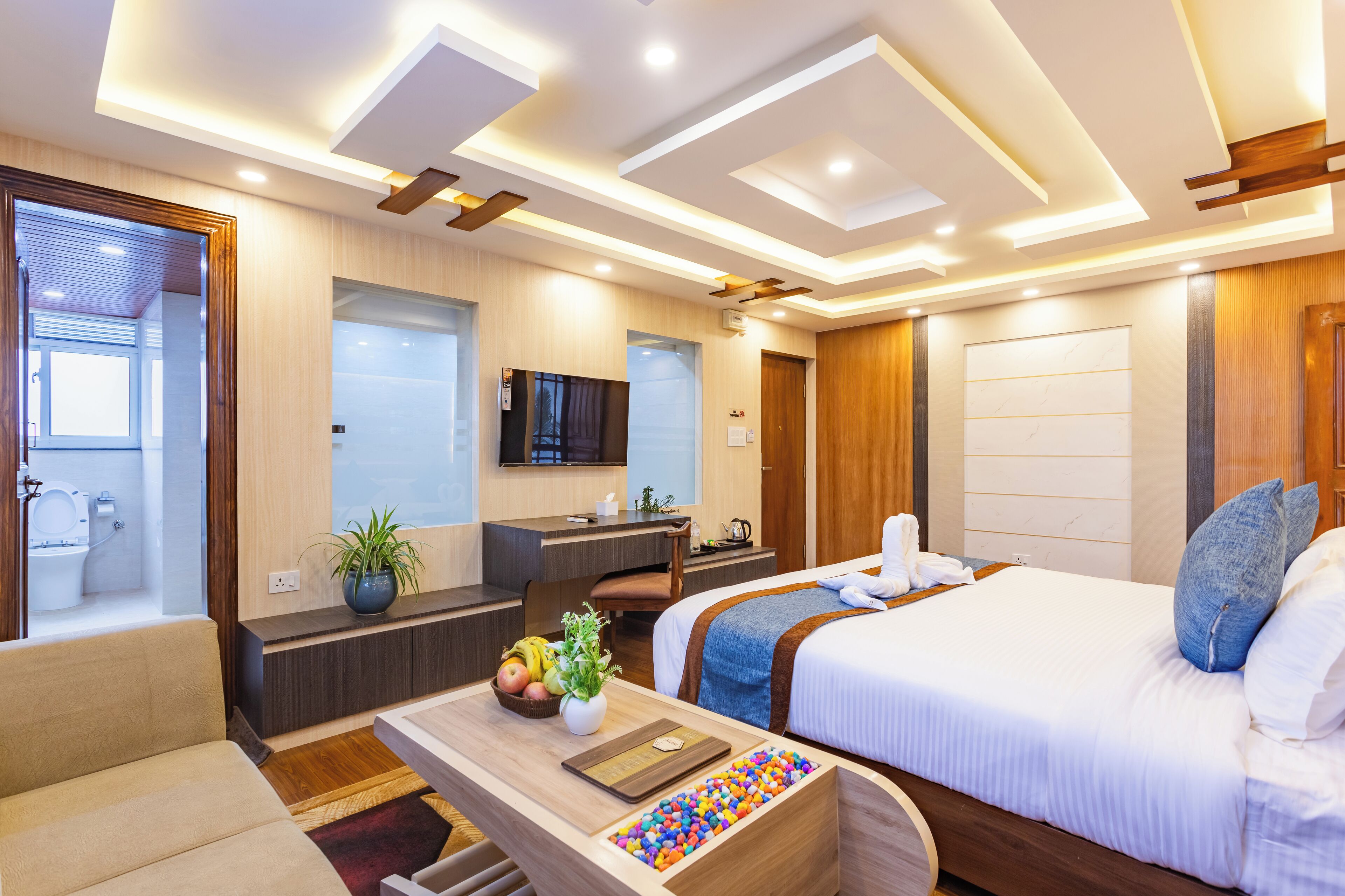 A modern hotel room with a bed, desk, and seating area.