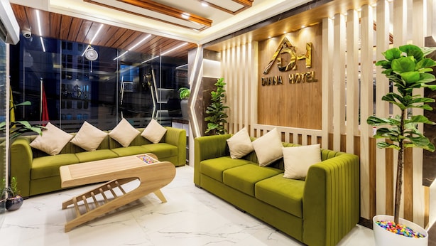 Un moderno vestíbulo de hotel con sofás verdes, detalles de madera y un mostrador de recepción.