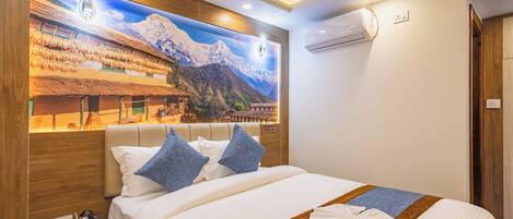 Habitación de hotel con una cama grande, una mesita de noche con hervidor y aire acondicionado instalado en la pared.
