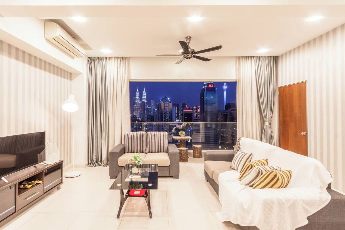 Un salon moderne avec vue sur la ville, doté d’un ventilateur de plafond et d’un téléviseur.