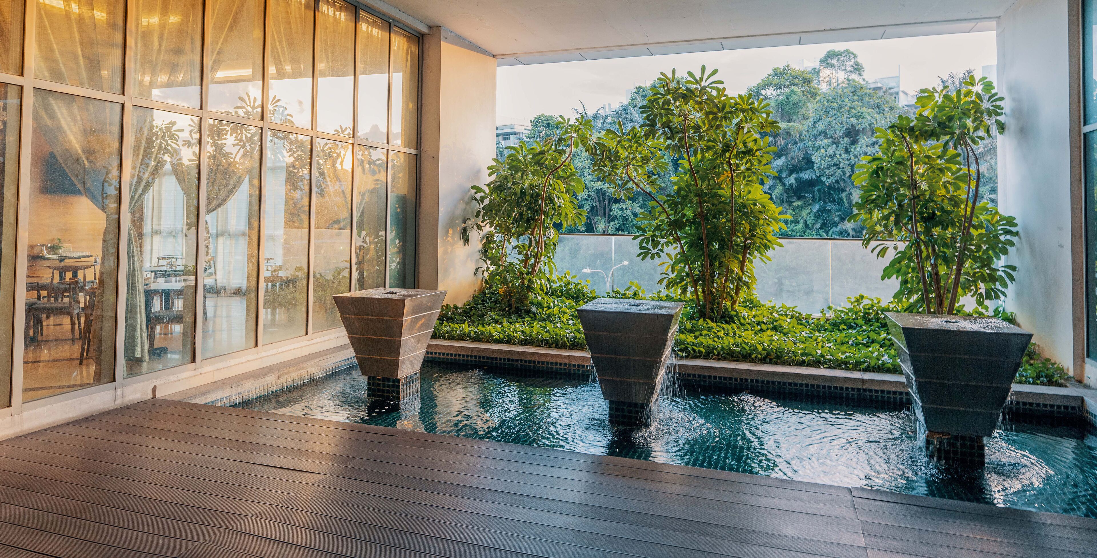 A modern indoor pool area with three stone planters and a wooden deck.