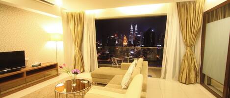 A modern living room with a sofa, TV, and a view of a cityscape at night.