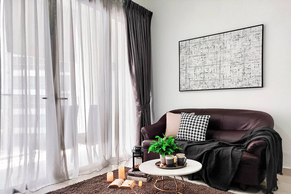 Un salon moderne avec un canapé en cuir marron, une table basse blanche et un grand tableau abstrait accroché au mur.