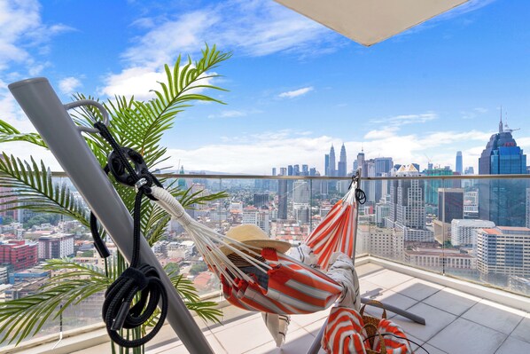 A hammock on a balcony with a cityscape view.
