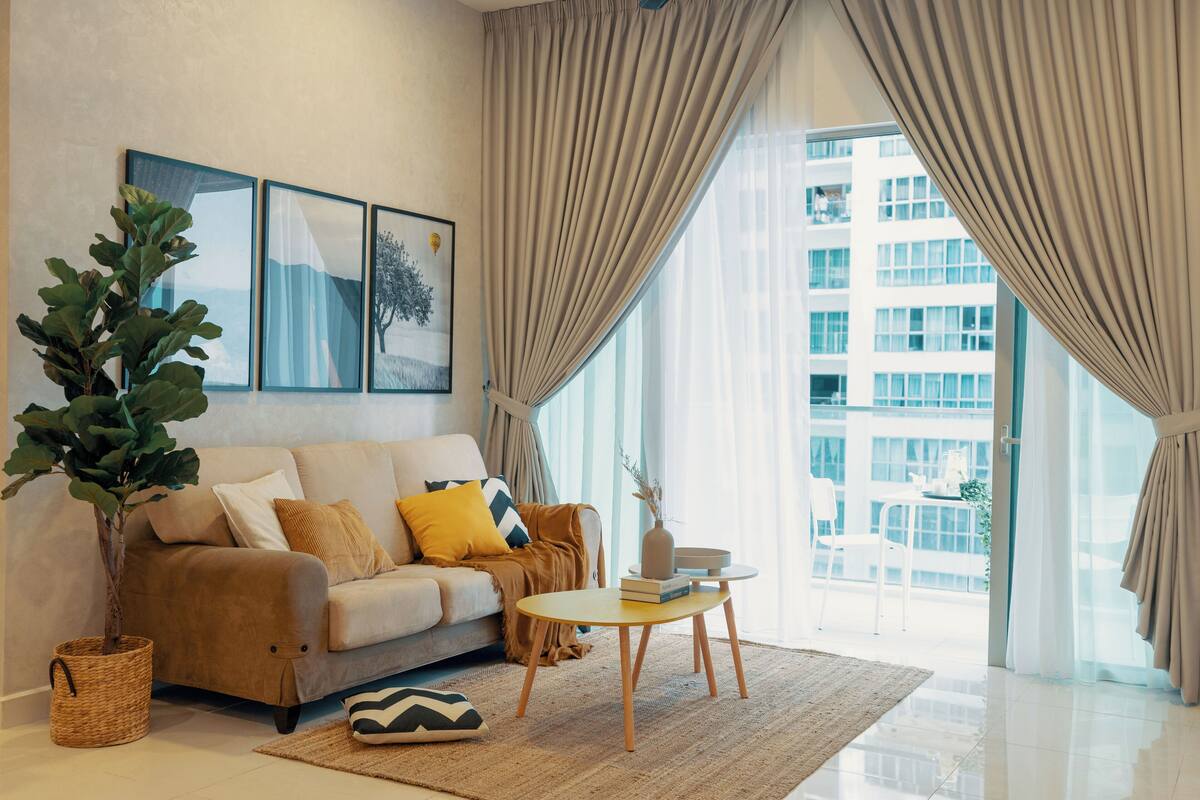 Un salon moderne avec un canapé, une table basse et une grande fenêtre agrémentée de rideaux.