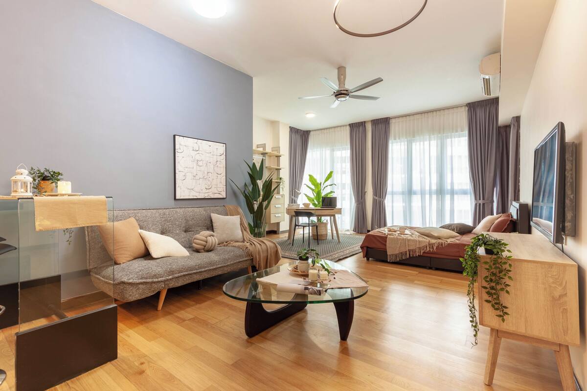 Un salon moderne avec une table basse en verre, un canapé, une table d’appoint en bois et un ventilateur de plafond.