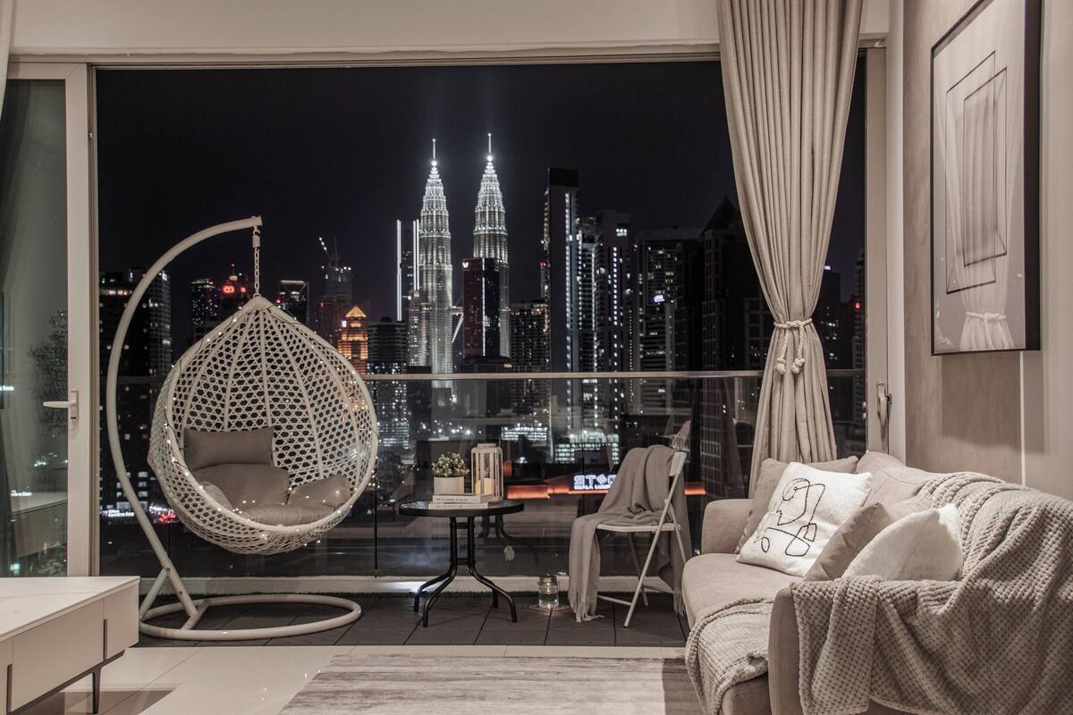 Un salon moderne offrant une vue sur les tours Petronas la nuit.