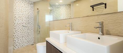Un baño moderno con dos lavamanos, ducha e inodoro.