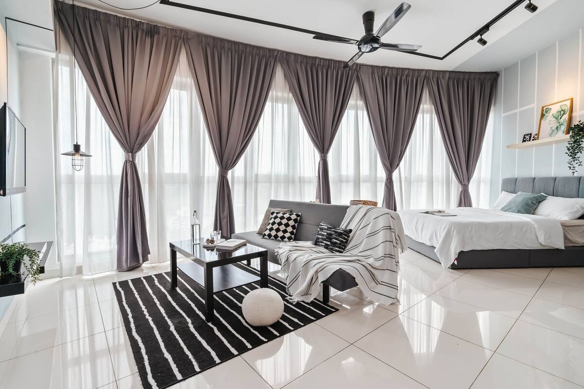 Une chambre à coucher moderne avec un lit, un canapé, une table basse et un ventilateur de plafond.