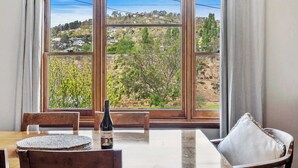 A dining area with a table, chairs, and a bottle of wine. - "Cascade Cottage" South Hobart with parking (South Hobart)