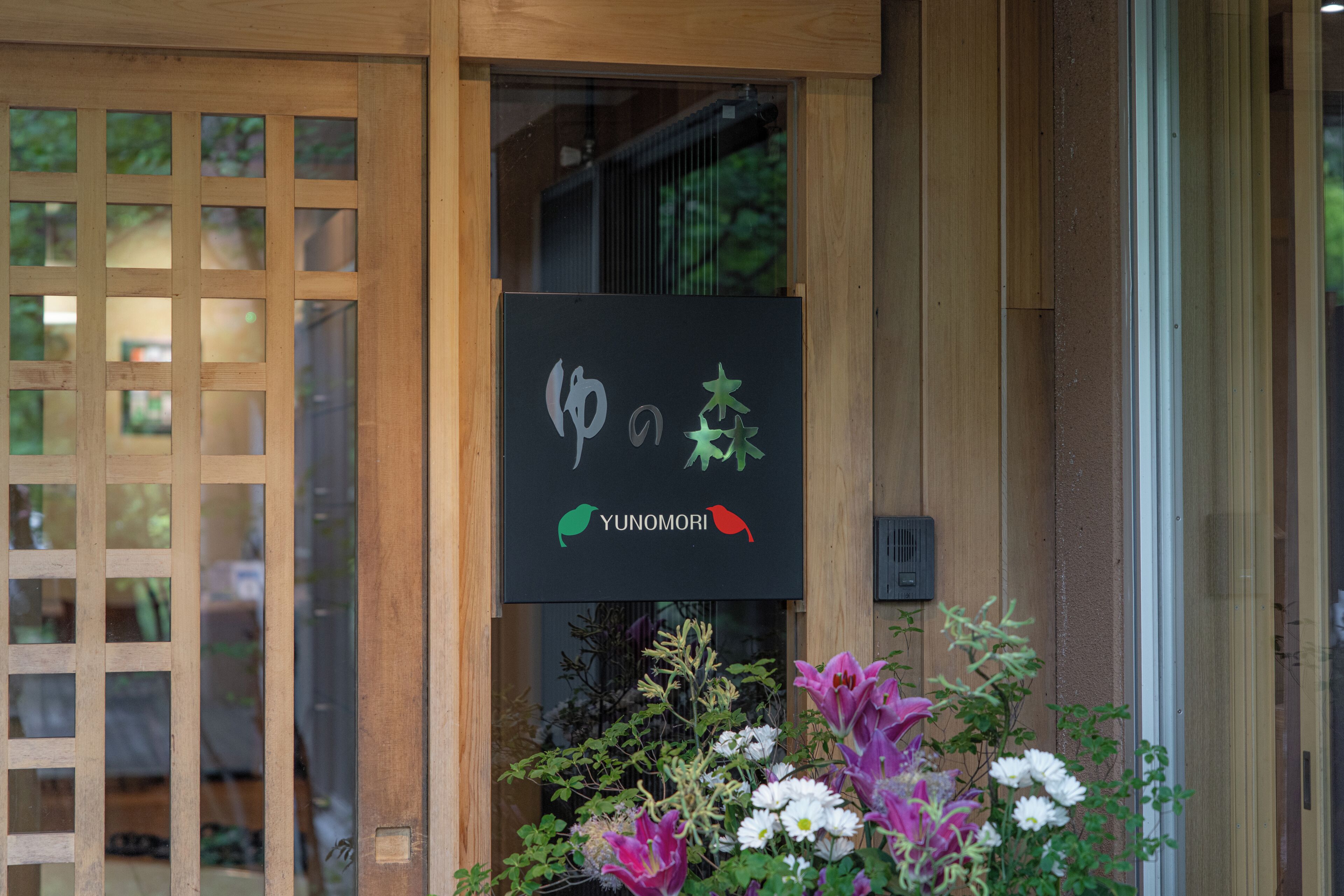 A wooden entrance with a black sign featuring a bird and a plant.