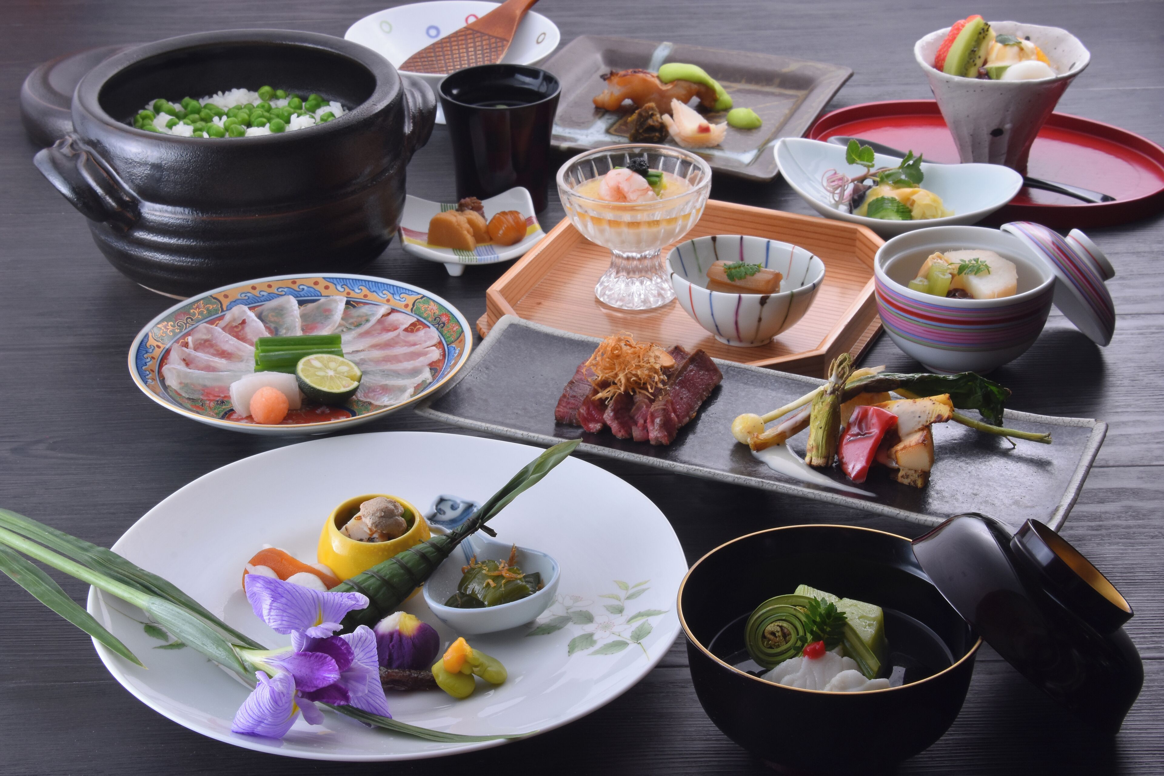 Une variété de plats japonais disposés sur une table en bois, notamment des sushis, des sashimis et un plat de riz.