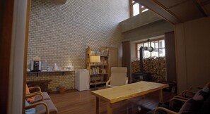 Una habitación acogedora con pared de ladrillo, una mesa de madera, una estantería, una silla y una chimenea.