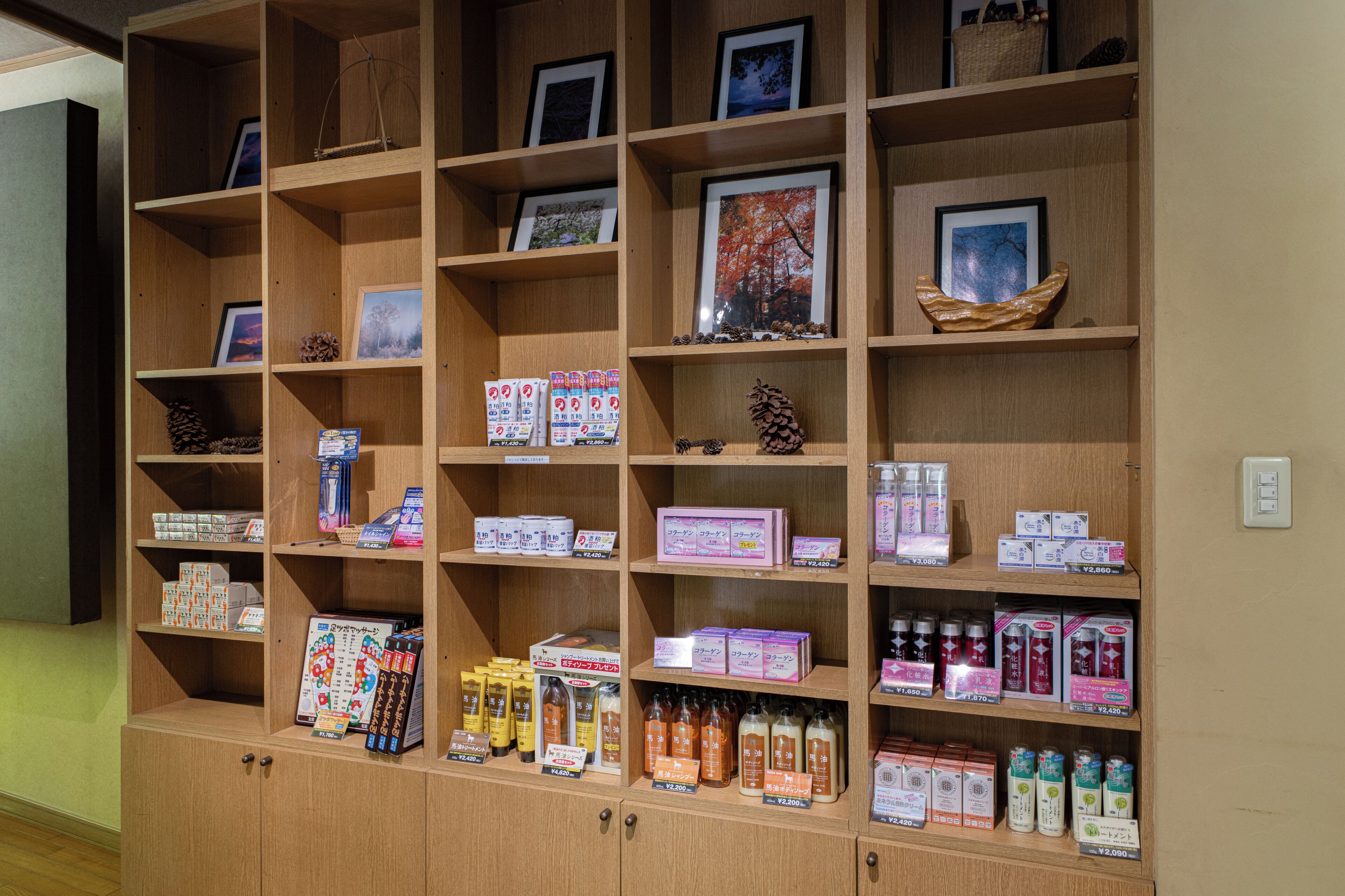 A wooden display shelf with various products and framed pictures.