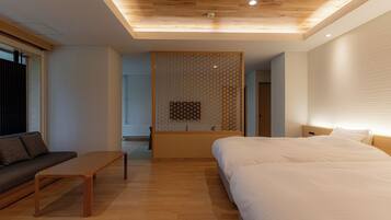 A modern hotel room with a wooden ceiling, a bed, a sofa, and a small table.