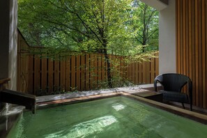 A spa area with a hot tub, wooden fence, and a chair. - Okunikko Yumoto Onsen Yunomori (Nikko)
