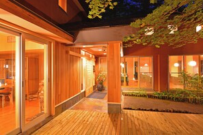 A wooden exterior of a building with large glass doors and windows, a wooden deck, and a potted plant. - Okunikko Yumoto Onsen Yunomori (Nikko)