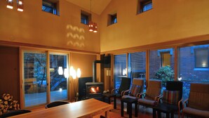 A cozy living room with a fireplace, wooden furniture, and large windows offering a view of the outdoors. - Okunikko Yumoto Onsen Yunomori (Nikko)
