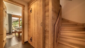 A wooden staircase leading to a second floor, a wooden wardrobe, and a view of a garden through a glass door.