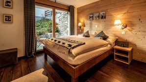 Une chambre avec un grand lit, des murs en bois et une vue sur la verdure.